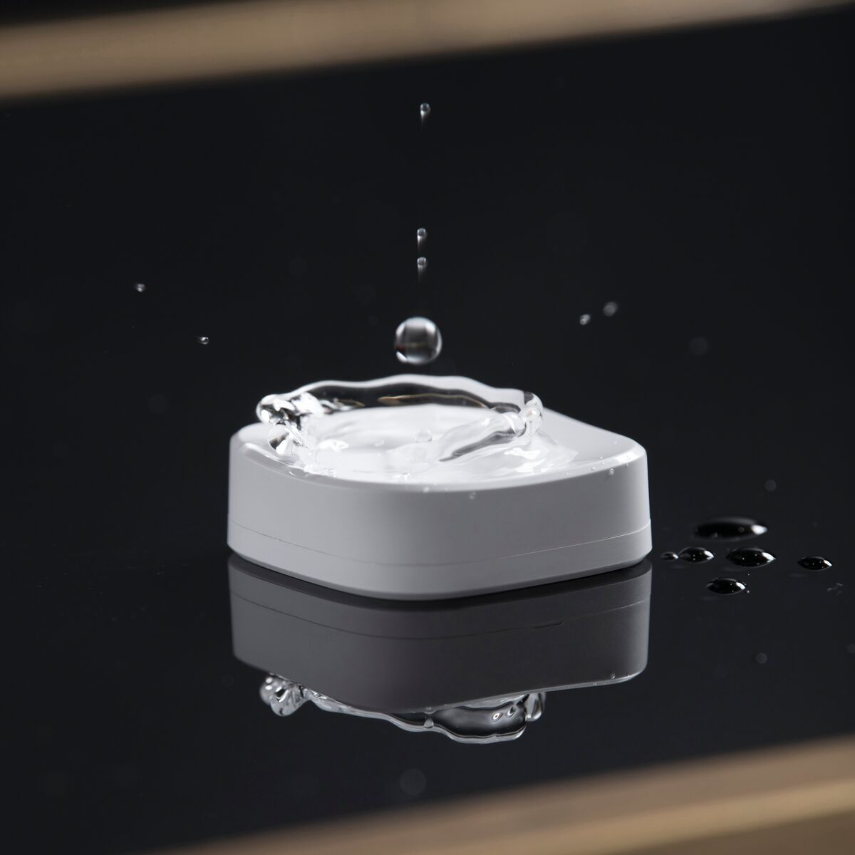 Sense MA - Zigbee Water Detector - Close up of a water drop falling apart on the Sense MA Water Detector | Marmitek